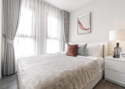 Spacious and bright bedroom with large windows, modern decor, and a comfortable bed