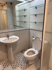 Bathroom with large mirror, sink, toilet, and glass shelves