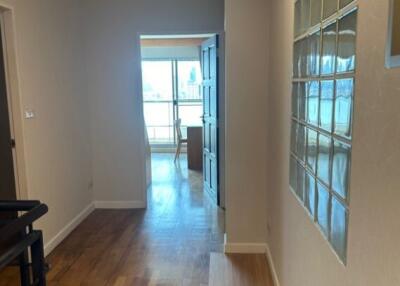 Spacious hallway with wooden flooring and glass block window