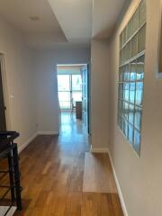 Spacious hallway with wooden flooring and glass block window