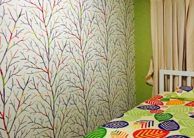 Colorful bedroom with tree-patterned wallpaper and bed with vibrant leaf-patterned bedspread