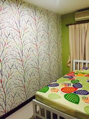 Colorful bedroom with tree-patterned wallpaper and bed with vibrant leaf-patterned bedspread