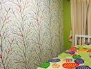 Colorful bedroom with tree-patterned wallpaper and bed with vibrant leaf-patterned bedspread