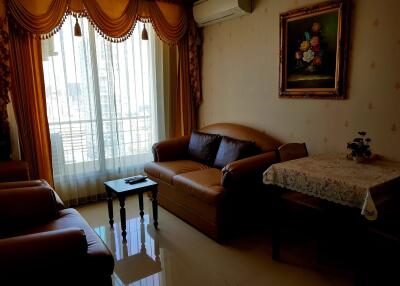 Living room with sofa, armchairs, coffee table, wall-mounted air conditioner, and large window with drapes