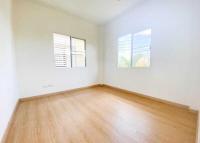 Spacious empty bedroom with wooden floors and two windows