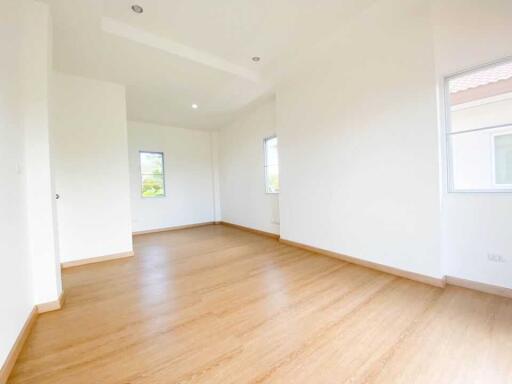 Spacious empty bedroom with wooden flooring and natural light