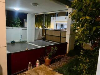 Covered balcony overlooking residential area with plants and stairs