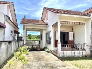 Front view of a small house with a driveway and garden