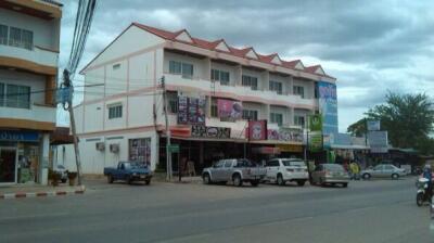 Street view of a multi-story commercial building with shops on the ground floor