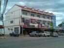 Street view of a multi-story commercial building with shops on the ground floor