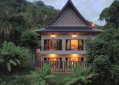 A two-story house surrounded by lush greenery