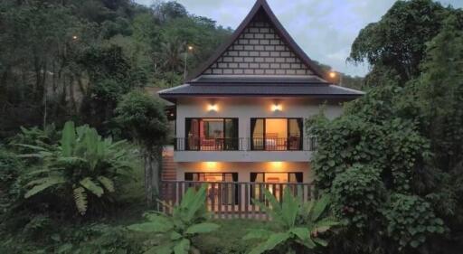 A two-story house surrounded by lush greenery