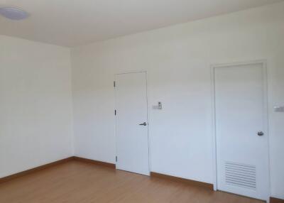 An empty bedroom with white walls and closed doors.