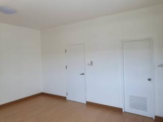 An empty bedroom with white walls and closed doors.