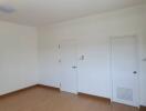 An empty bedroom with white walls and closed doors.