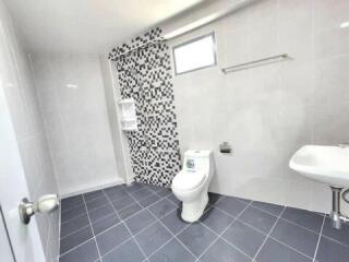 Spacious modern bathroom with tiled flooring and mosaic feature wall