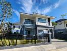 Modern two-story house exterior with a fenced yard