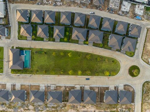 Aerial view of a modern housing development with identical houses and central green area