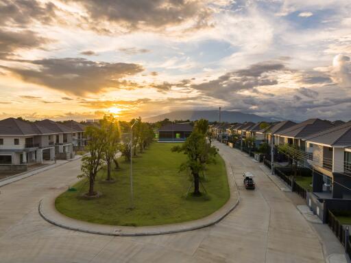 Aerial view of a modern suburban neighborhood with a central park area at sunset