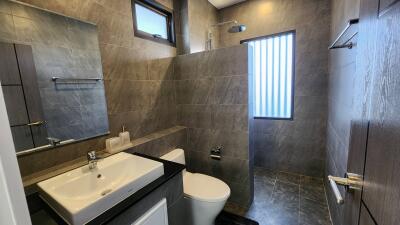 Modern bathroom with gray tiles, glass shower, and white fixtures