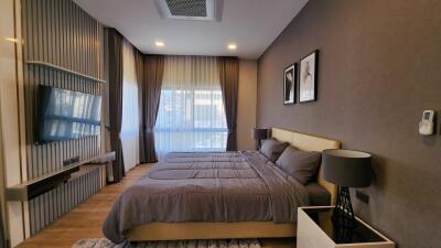 Modern bedroom with mounted TV and large windows