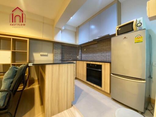 Modern kitchen with wooden cabinets, built-in oven, and refrigerator