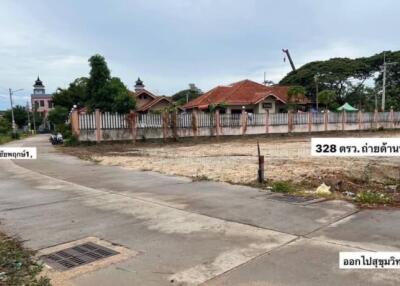 Empty lot with a concrete path and fenced houses in the background