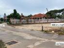 Empty lot with a concrete path and fenced houses in the background