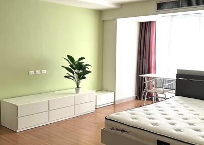 Bedroom with a bed, dresser, plant, and a small table near the window