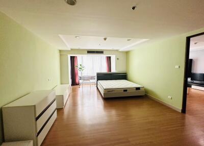 Spacious bedroom with a bed, dresser, and large windows