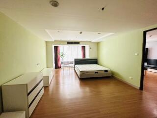 Spacious bedroom with a bed, dresser, and large windows