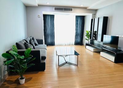 Modern living room with wooden flooring, sofa, coffee table, TV unit, and indoor plants