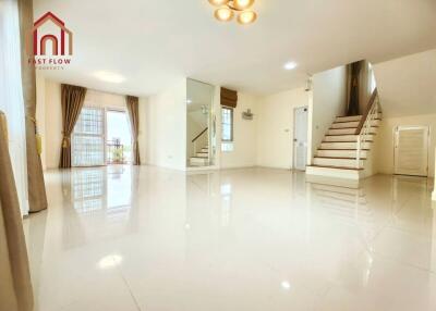 Spacious modern living room with polished flooring, staircase, and ample natural light