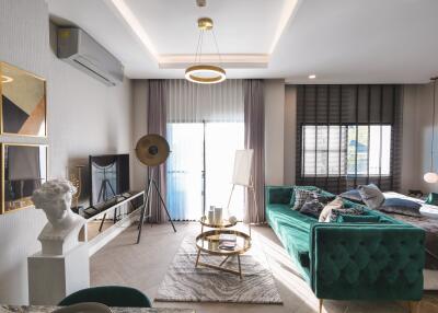 Modern living room with green velvet couch and large windows