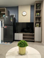 Modern living room with TV, refrigerator, and decorative elements