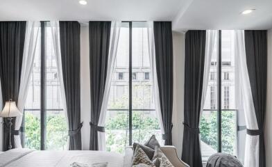 Modern bedroom with large windows and dark curtains