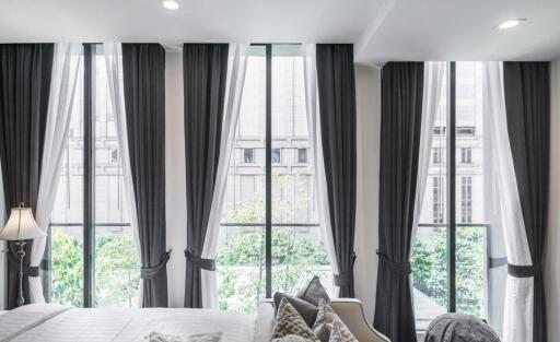 Modern bedroom with large windows and dark curtains