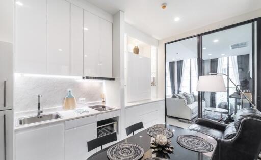 Modern kitchen and living room with sleek white cabinetry, dining table, and cozy seating area