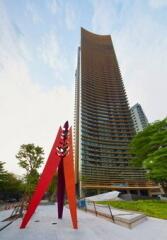 Modern high-rise residential building with unique red and purple sculpture in front