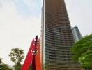 Modern high-rise residential building with unique red and purple sculpture in front