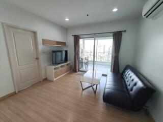 Modern living room with a couch, TV, and access to balcony