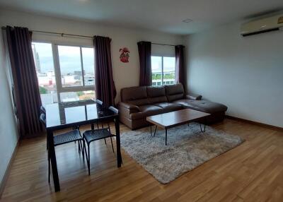 Spacious living room with wooden floor, large windows, and modern furniture