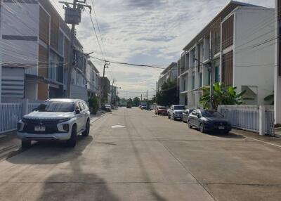 A view of a residential street lined with modern townhouses and parked cars.