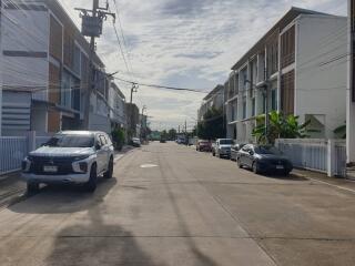 A view of a residential street lined with modern townhouses and parked cars.