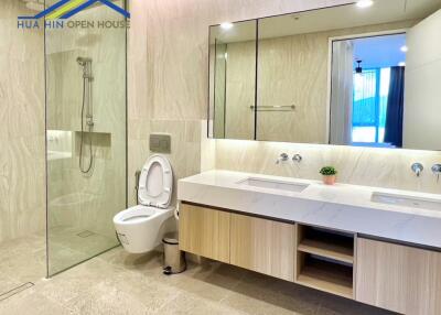 Modern bathroom with a glass shower, dual sinks, and a toilet.
