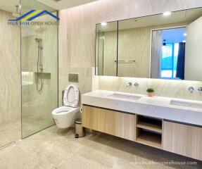 Modern bathroom with a glass shower, dual sinks, and a toilet.