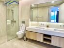 Modern bathroom with a glass shower, dual sinks, and a toilet.