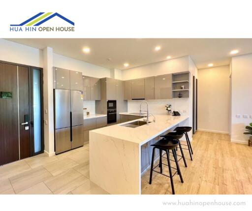 Modern kitchen with island, stainless steel appliances, and wooden flooring