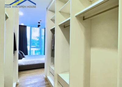 Spacious walk-in closet with open shelving and drawers, view into bedroom