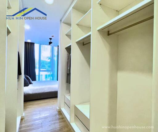 Spacious walk-in closet with open shelving and drawers, view into bedroom